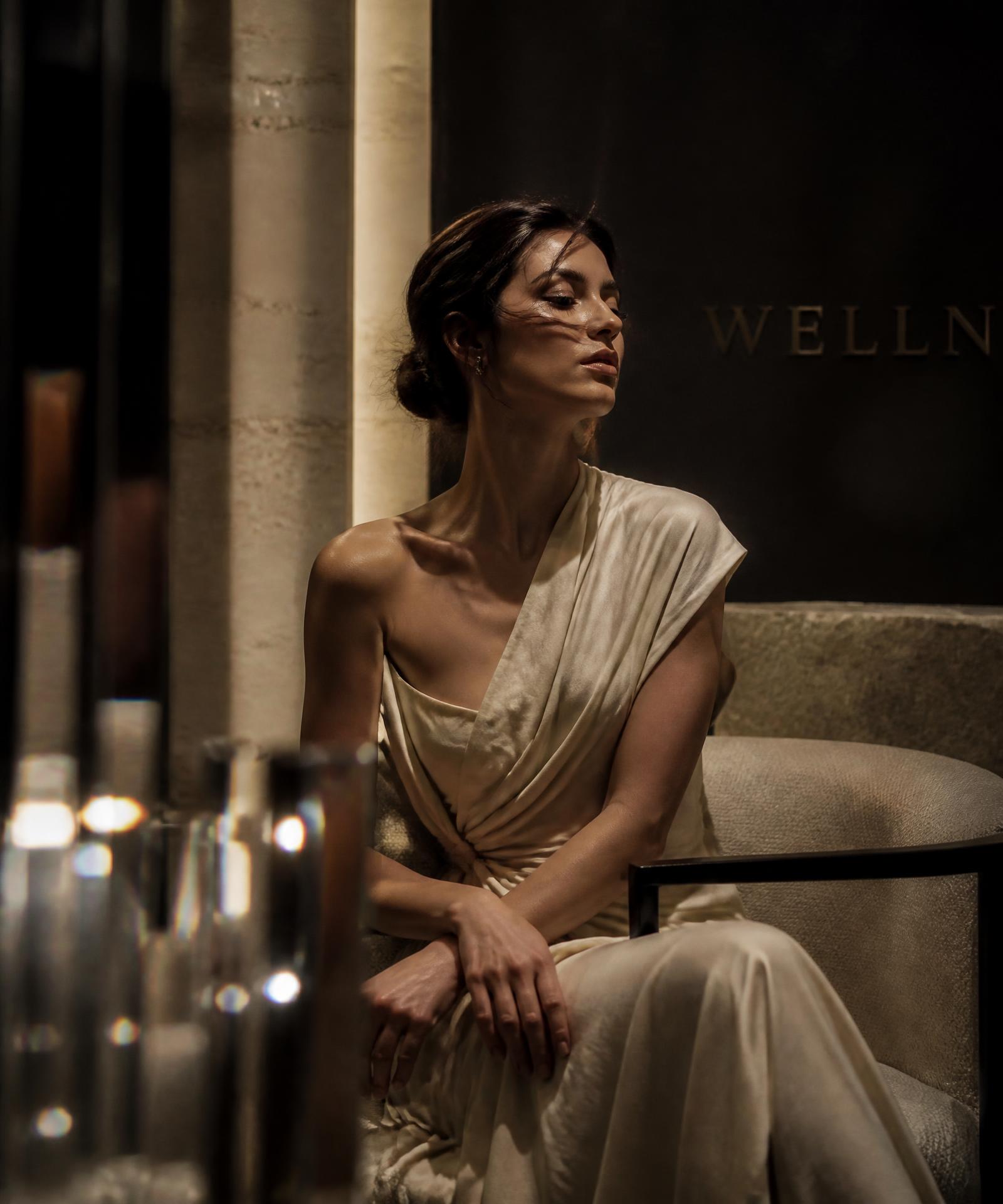 A guest seated in the softly lit ivory and stone interior of Crystal Luxe Wellness Center
